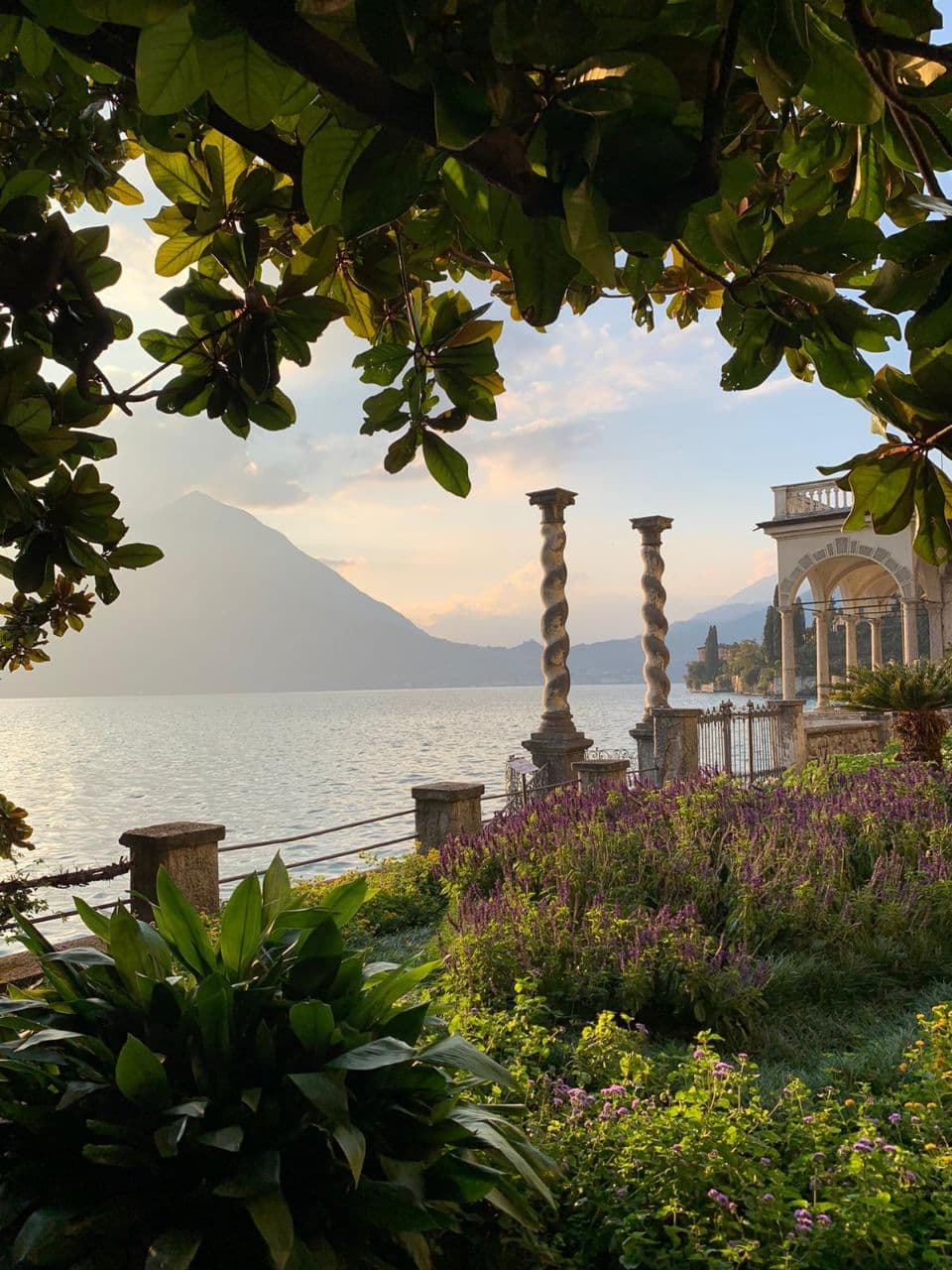 Villa Monastero garden beside Lake Como, with columns, flowers, and mountain views